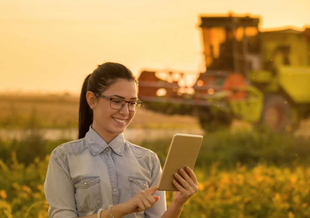 A woman with a tablet device stands in a field