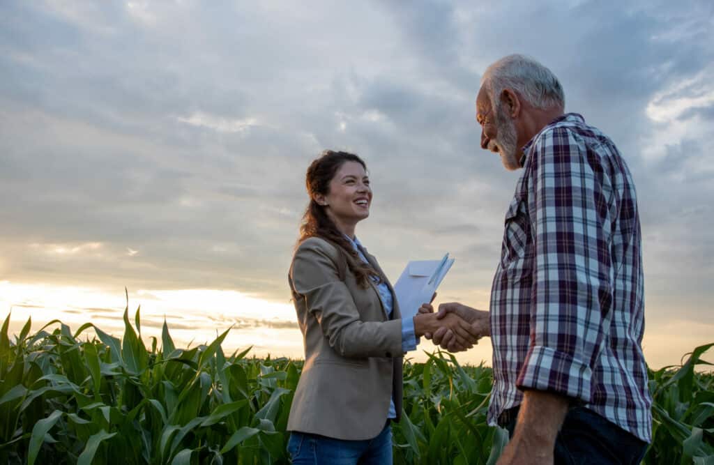 Man and woman shaking hands in a field at dusk