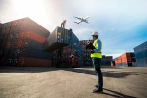 A man stands by shipping containers on a dockyard.