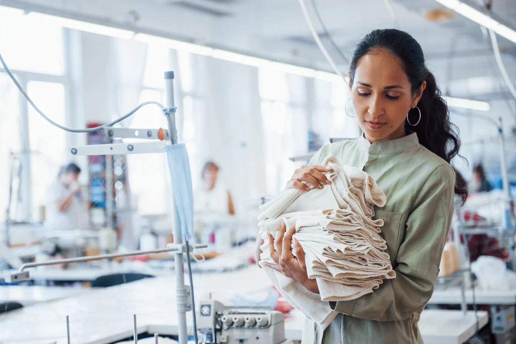 Woman in a garment factory holding folded textiles
