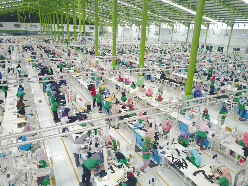 Garment workers at sewing stations in a large apparel factory