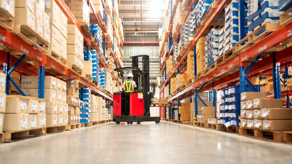 Forklift operator moving pallets in a retail supply chain warehouse