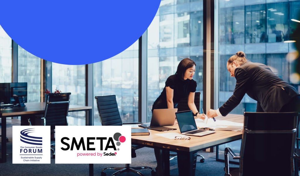 Two people in an office lean over a table with laptops on it